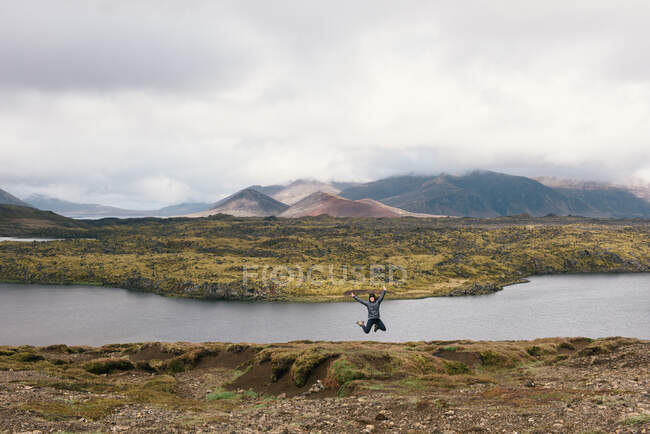 Jovem pulando de alegria na vista panorâmica da Islândia com montanhas — Fotografia de Stock