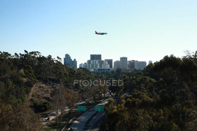 An airplane flys plast the San Diego skyline on its landing approach — Stock Photo