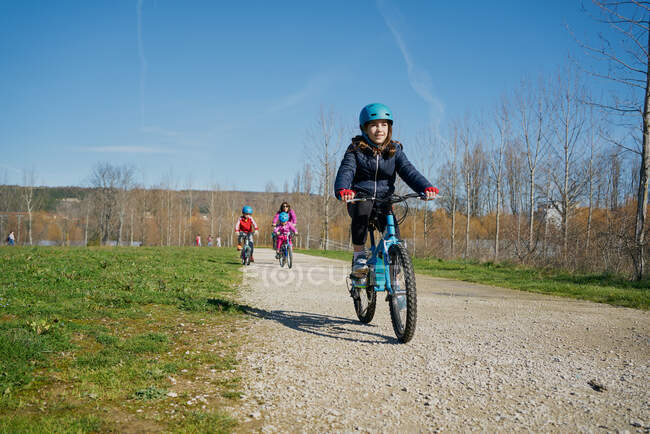 Fille en vélo en face de sa famille à venir derrière — Photo de stock