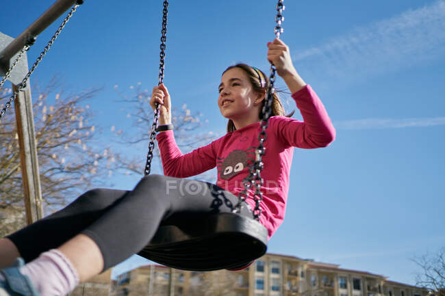 Menina em um balanço com um fundo céu azul — Fotografia de Stock