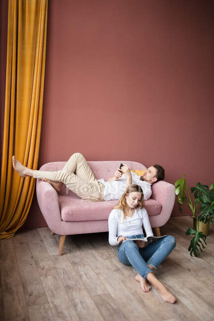 Junges verliebtes Paar sitzt auf Sofa und liest Buch — Stockfoto