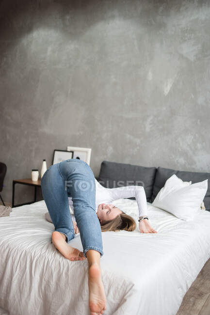 Mujer joven acostada en la cama en el dormitorio - foto de stock