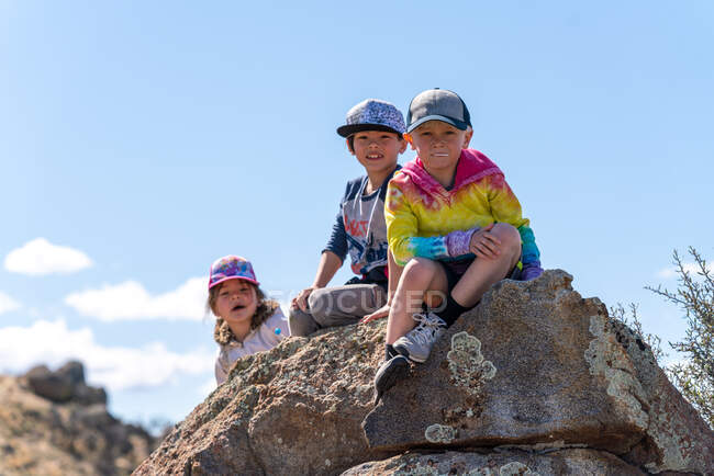 Kinder sitzen auf einem Felsen und schauen in die Kamera — Stockfoto