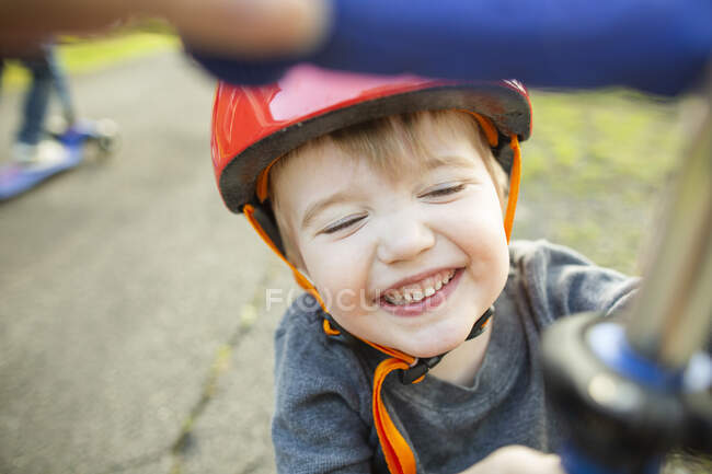Усміхнений молодий хлопчик в червоному шоломі грає на вулиці вдома — стокове фото