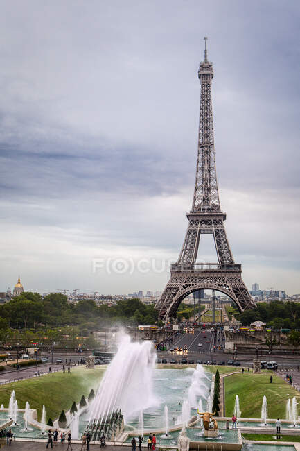 Ейфелева вежа в Парижі з сірим небом і фонтаном спереду. — стокове фото