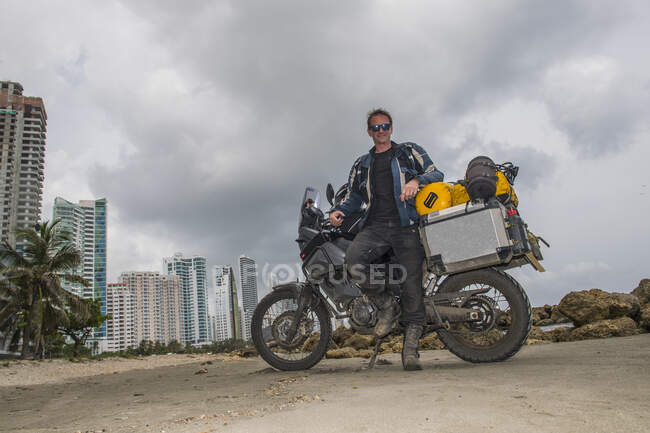 Hombre posando junto a su moto de aventura después de un largo viaje, Columbia - foto de stock