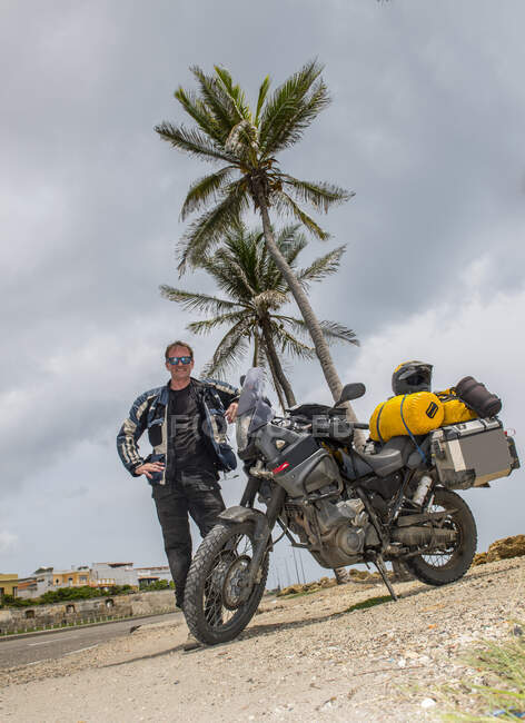 Человек позирует рядом со своим приключенческим мотоциклом после долгого путешествия, Колумбия — стоковое фото