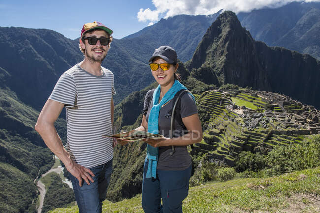 Pareja en ruinas incas mirando a la cámara sonriendo, Machu Picchu, Perú - foto de stock