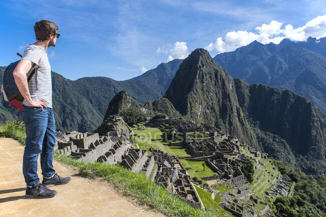 Человек, стоящий, глядя на вид руин инков, Мачу-Пикчу, Перу — стоковое фото