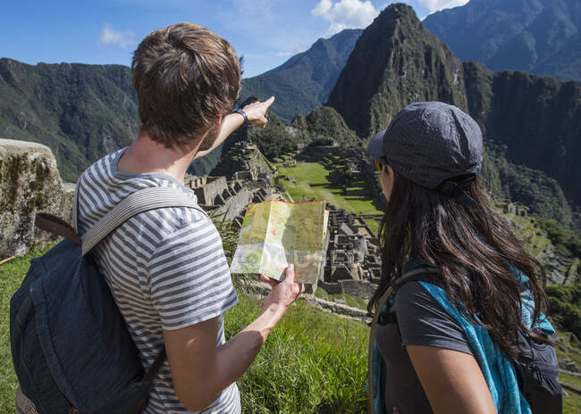 Пара на руинах инков глядя на складывающуюся карту, Мачу-Пикчу, Перу — стоковое фото