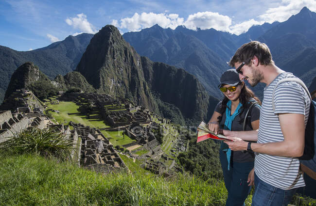 Couple at Inca ruins looking at folding map, Machu Picchu, Peru — Stock Photo
