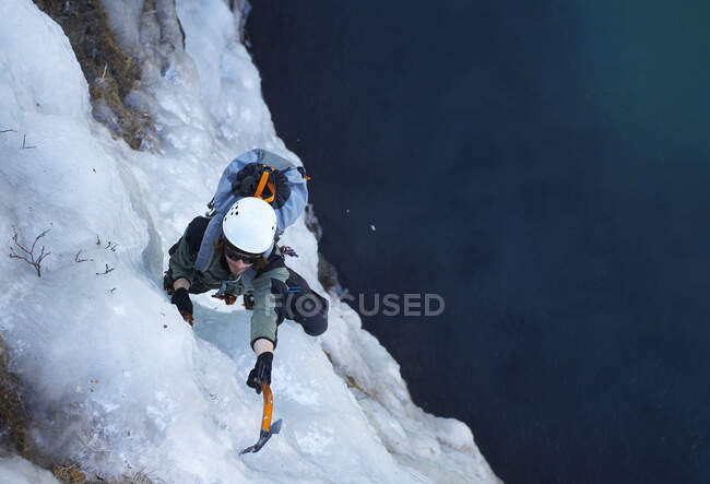 Young man climbing frozen waterfall in Iceland — Stock Photo