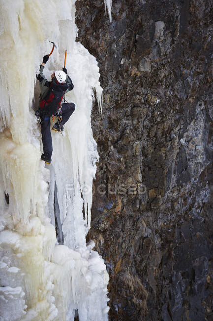 Молодой человек карабкается на замерзший водопад в Исландии — стоковое фото