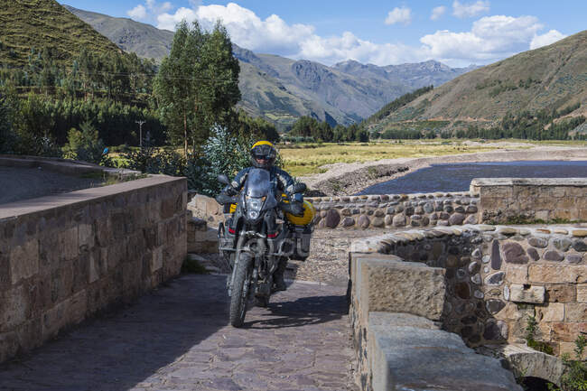 Conducción de motos sobre un puente del río Urubamba, Perú - foto de stock