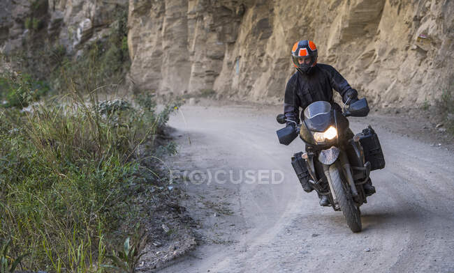 Мужчина за рулем мотоцикла на скользкой дороге, Санта-Терра, Пьюра, Перу — стоковое фото
