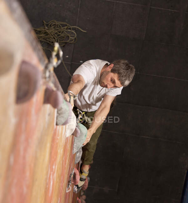 Mature man practising at indoor climbing wall in the UK — Stock Photo