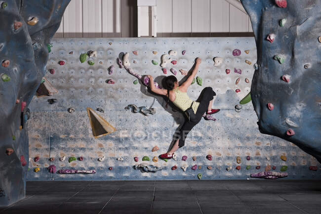 Mujer madura practicando en el muro de escalada interior en el Reino Unido - foto de stock