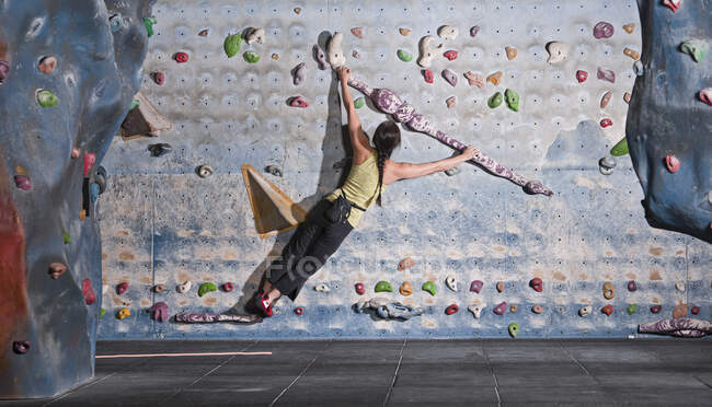 Mujer madura practicando en el muro de escalada interior en el Reino Unido - foto de stock