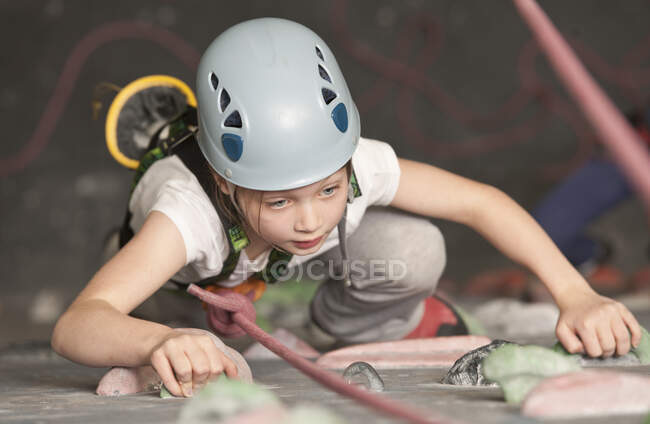 Jeune fille escalade au mur d'escalade intérieur en Angleterre / Royaume-Uni — Photo de stock