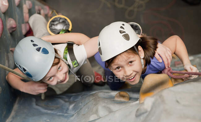 Deux jeunes filles grimpant au mur d'escalade intérieur en Angleterre / Royaume-Uni — Photo de stock