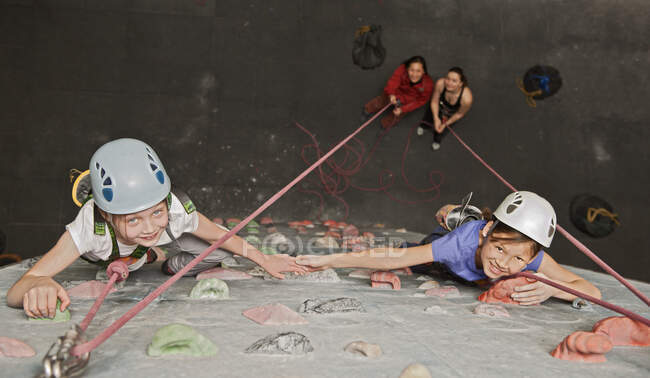 Dos chicas jóvenes escalando en el muro de escalada interior en Inglaterra / Reino Unido - foto de stock