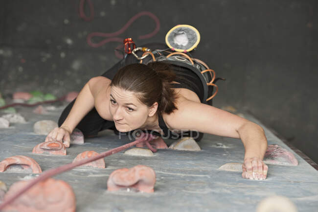 Jeune femme escalade au mur d'escalade intérieur en Angleterre / Royaume-Uni — Photo de stock