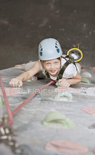 Молодая девушка лазает по скалолазанию в помещении в Англии / Великобритании — стоковое фото
