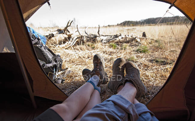Пара лежит в палатке с ногами снаружи — стоковое фото
