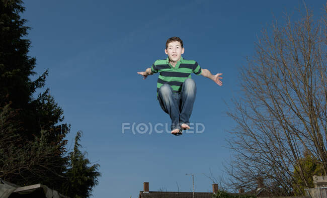 Chico saltando en trampolín en Woking - Inglaterra - foto de stock