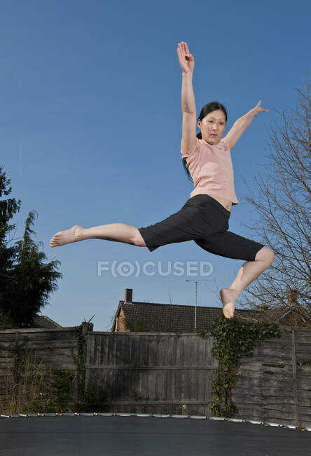 Mujer madura saltando sobre trampolín en Woking - Inglaterra - foto de stock