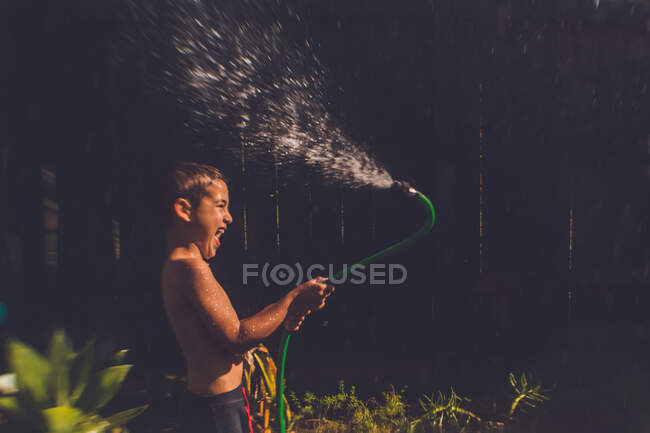 Junge spielt mit Schlauch im Hinterhof — Stockfoto