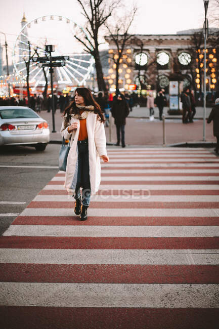 Продумана дівчина-підліток в теплому одязі, що перетинає дорогу в місті взимку — стокове фото