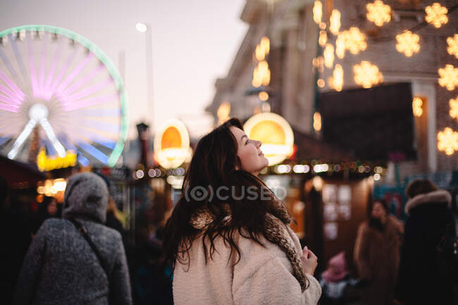 Heureuse adolescente profitant de la ville tout en marchant dans le marché de Noël le soir — Photo de stock