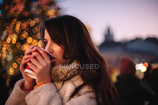 Ritratto di ragazza adolescente sognante che beve vin brulè nel mercatino di Natale — Foto stock