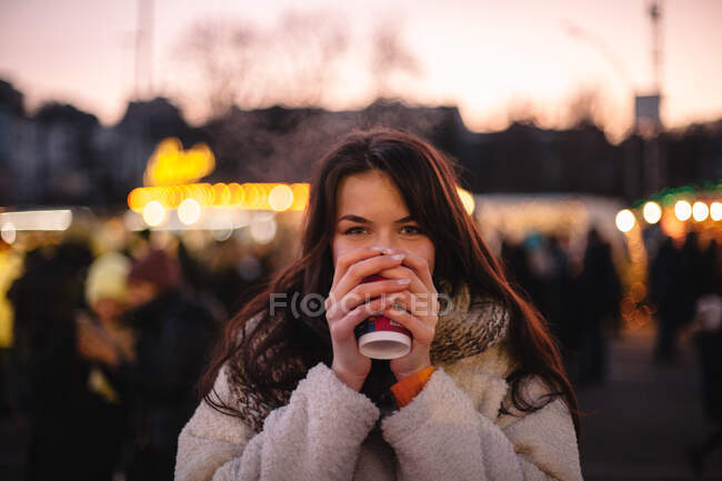 Ritratto di adolescente felice che beve vin brulè al mercatino di Natale in città — Foto stock