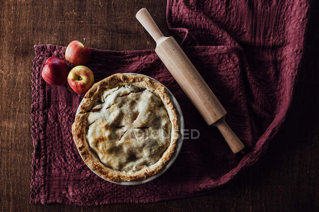 Overhead shot of apple pie with apples and rolling pin — Stock Photo