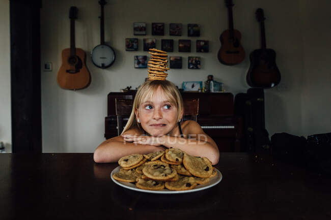 Menina jovem equilibrando biscoitos em sua cabeça — Fotografia de Stock
