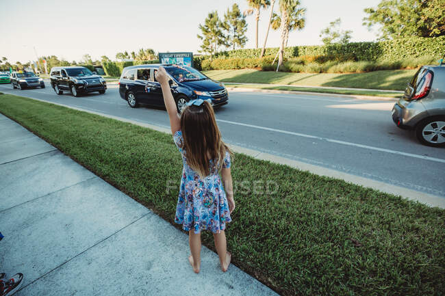 Young girl waves to her teachers during Shelter in Place car parade — Stock Photo