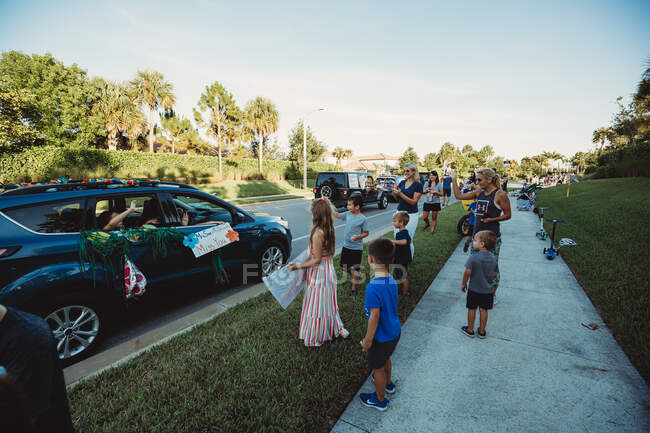 Des enfants saluent les enseignants lors d'un défilé automobile dans le quartier — Photo de stock