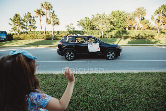 Kindergarten teacher waves to students in lockdown during parade — Stock Photo