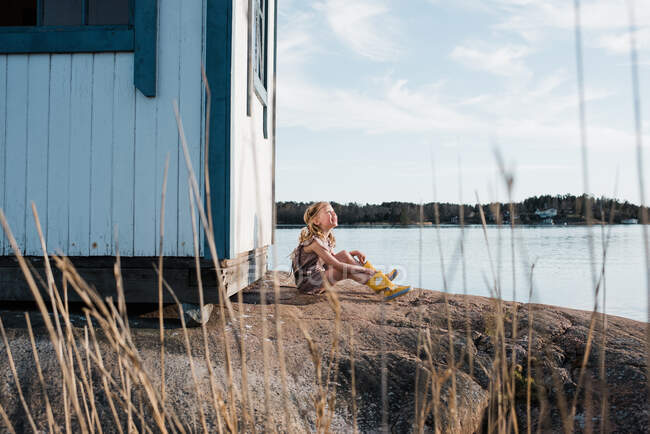 Portrait of adorable teen girl near old wooden shack on lake shore — Stock Photo
