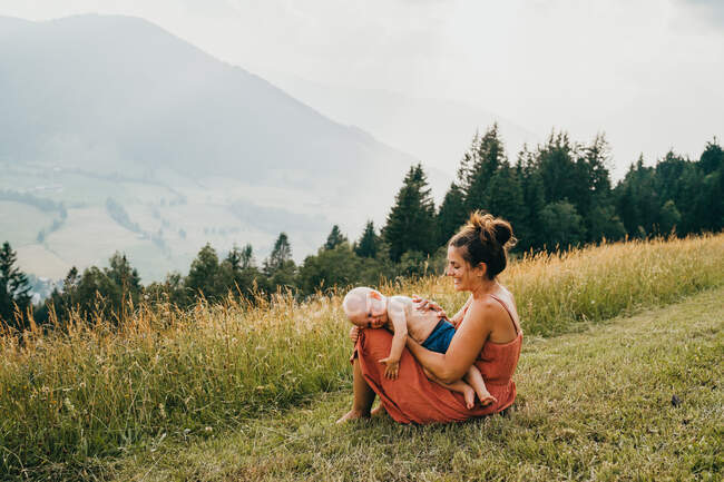 Madre joven con su hijo en las montañas - foto de stock