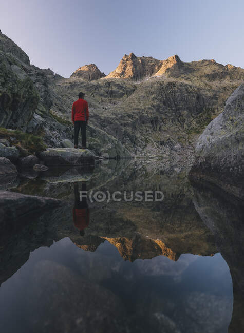 Un jeune homme se tient sur un rocher au lever du soleil à Sierra de Gredos, Avila, Espagne, — Photo de stock