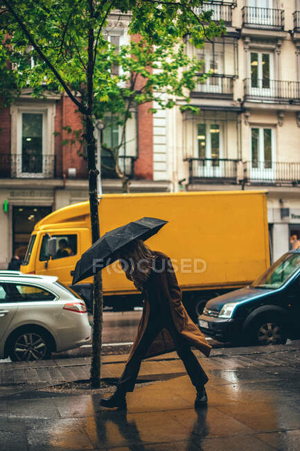 Frau läuft im Regen mit Regenschirm auf die Straße — Stockfoto