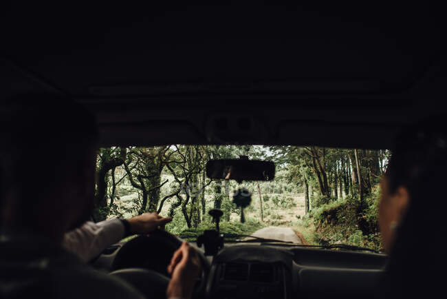 Un par de personas no reconocibles en un coche conduciendo por el bosque - foto de stock