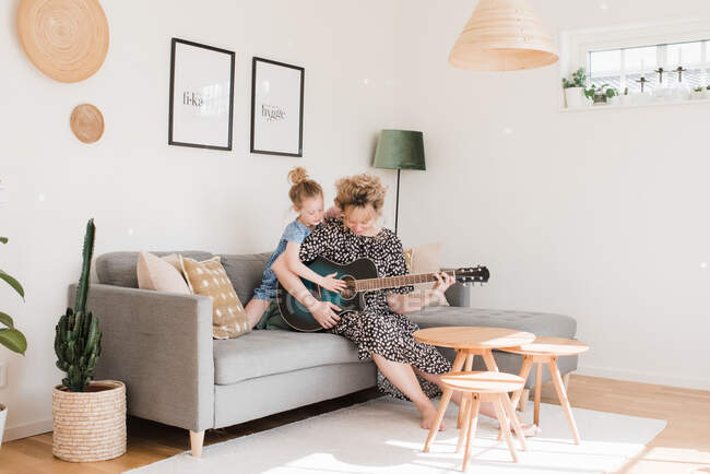 Mother and daughter playing guitar together at home — Stock Photo