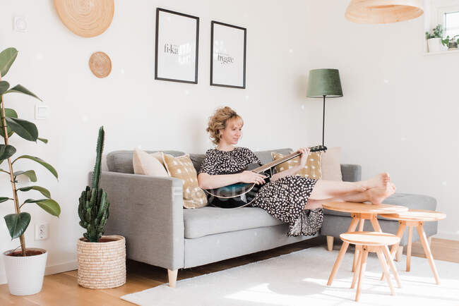 Frau saß zu Hause und spielte entspannt Gitarre — Stockfoto