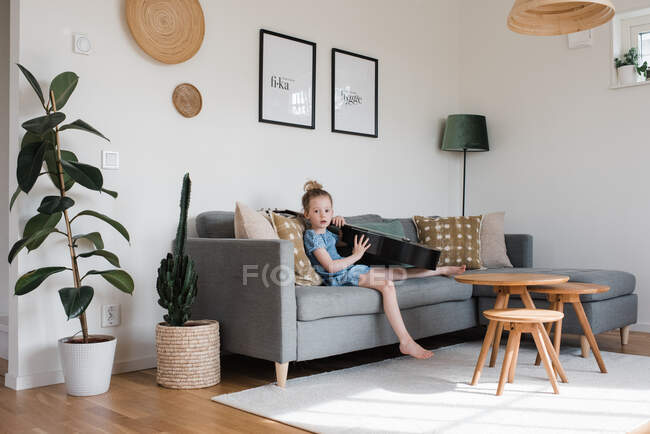 Young girl sat with a musical instrument, guitar at home — Stock Photo
