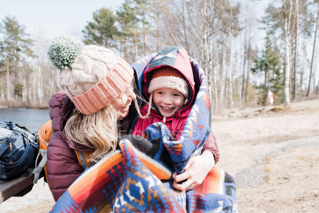 Mamá y su hija riendo y abrazándose mientras hacen un picnic - foto de stock
