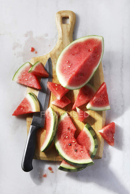 Fresh watermelon slices on chalkboard with knife, top view — Stock Photo